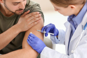 Doctor vaccinating young man in clinic